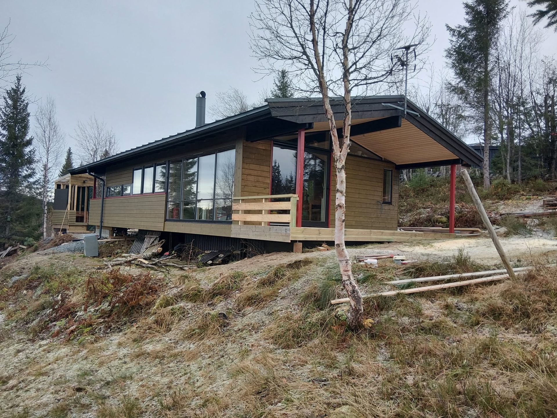 Moderne hytte med naturfarget trekledning og store panoramavinduer – nybygg av Byggservice 1 AS
