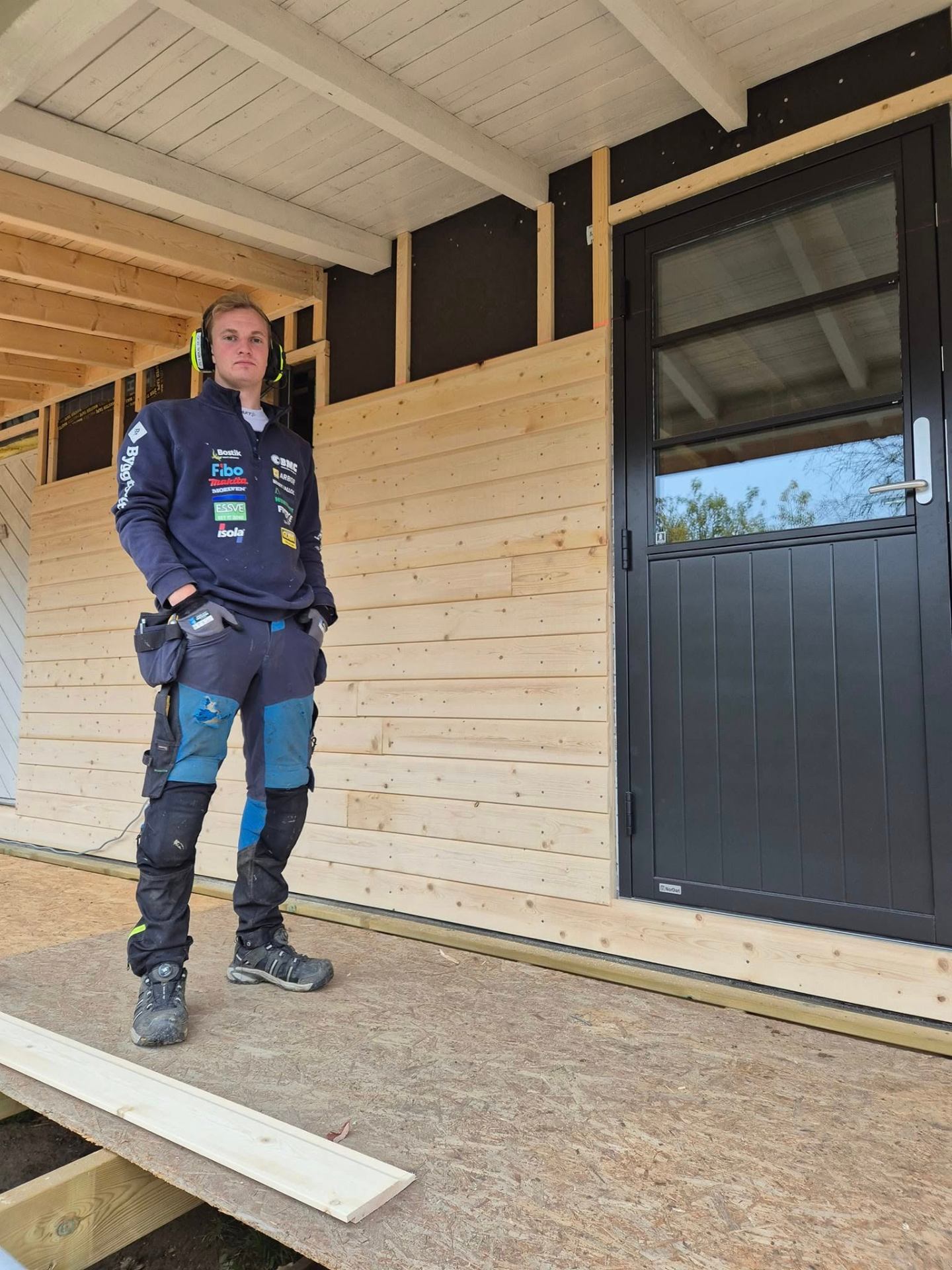 Tømrer fra Byggservice 1 AS foran nybygg med trekledning